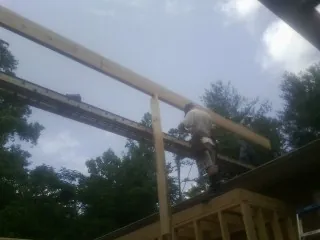 Carpenter setting a ridge beam over a new addition frame — Ice Dam Removal by Roofing Brothers in Saltillo