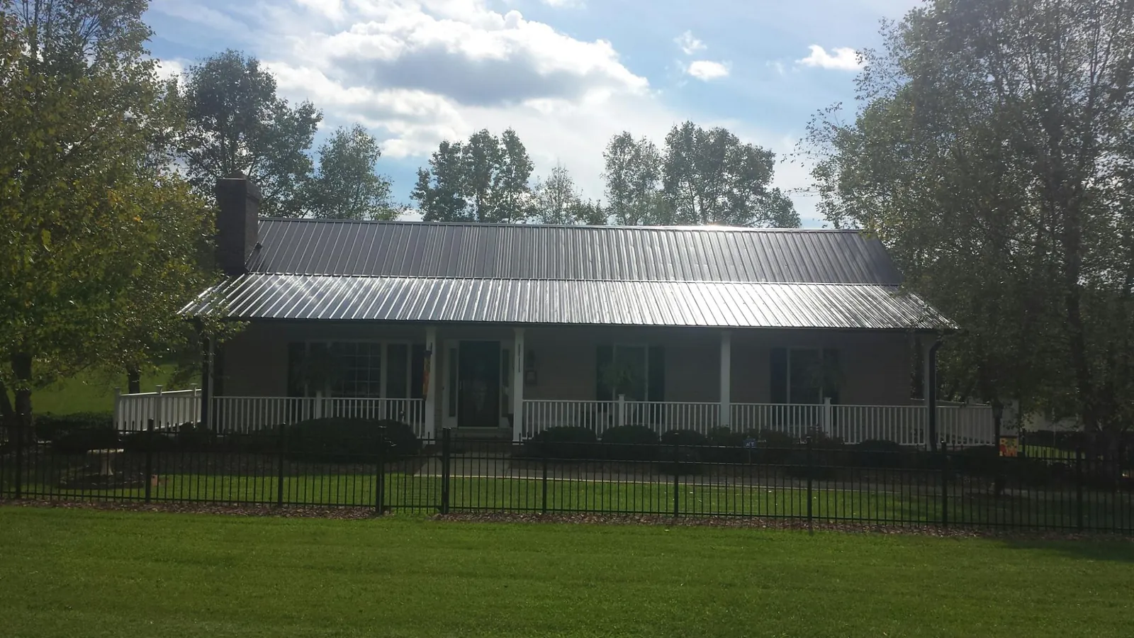 Gray metal roof on a brick ranch with a full width front porch — Gutter Guard Installation work by our crew in Saltillo